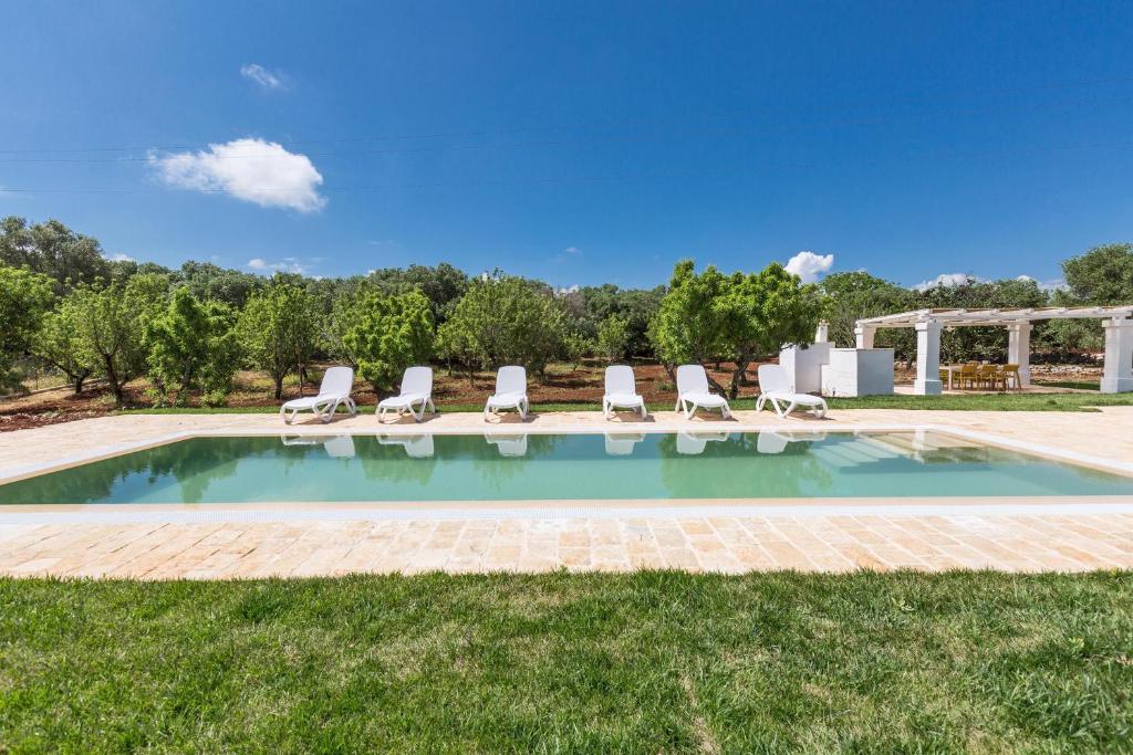a swimming pool with lounge chairs in the grass at Casale Amenola by Perle di Puglia in Ostuni