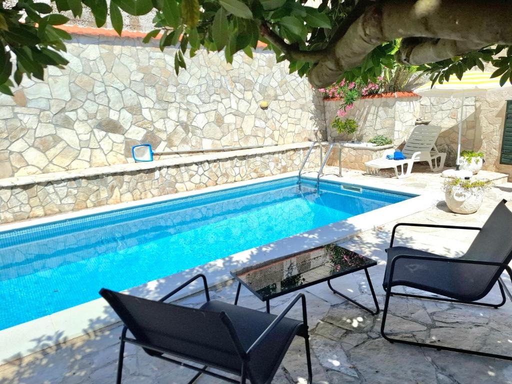 a swimming pool with two chairs and a table next to it at Villa Tina in Ploče