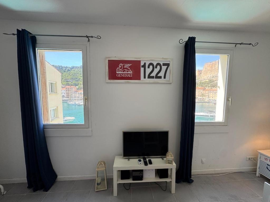 - un salon avec une télévision et 2 fenêtres dans l'établissement L'Ancrage - TV, Vue sur le port, Wi-Fi, à Bonifacio