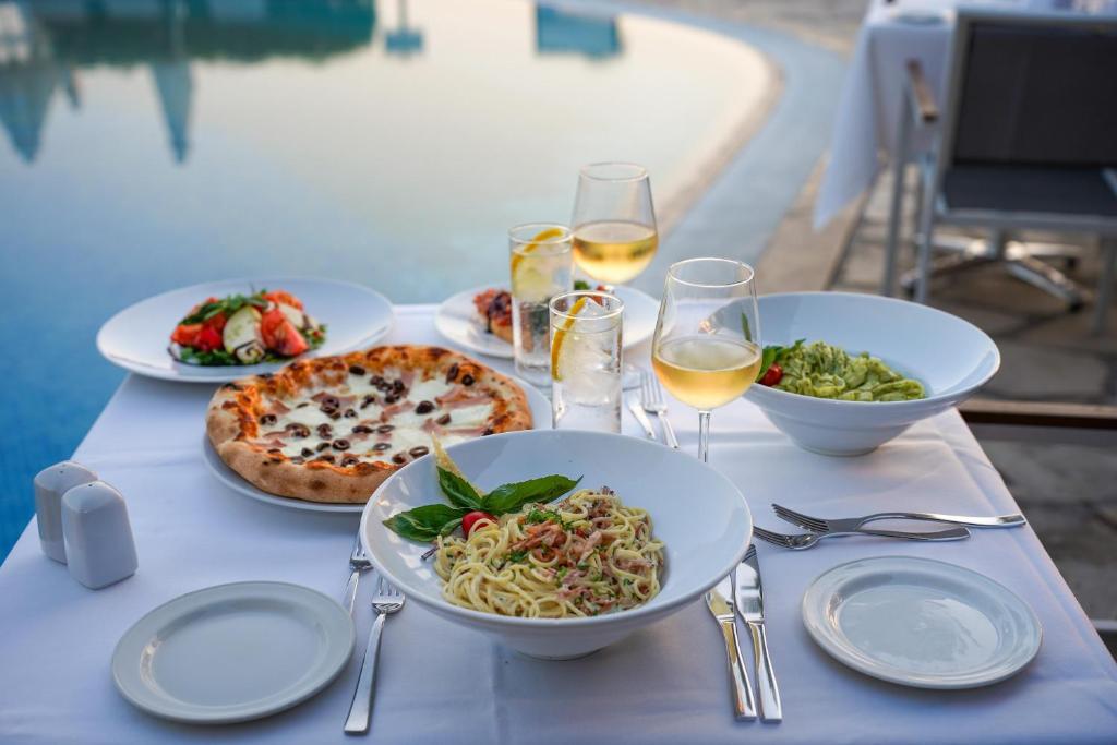a table with plates of food and glasses of wine at Coral Beach Hotel & Resort Cyprus in Coral Bay