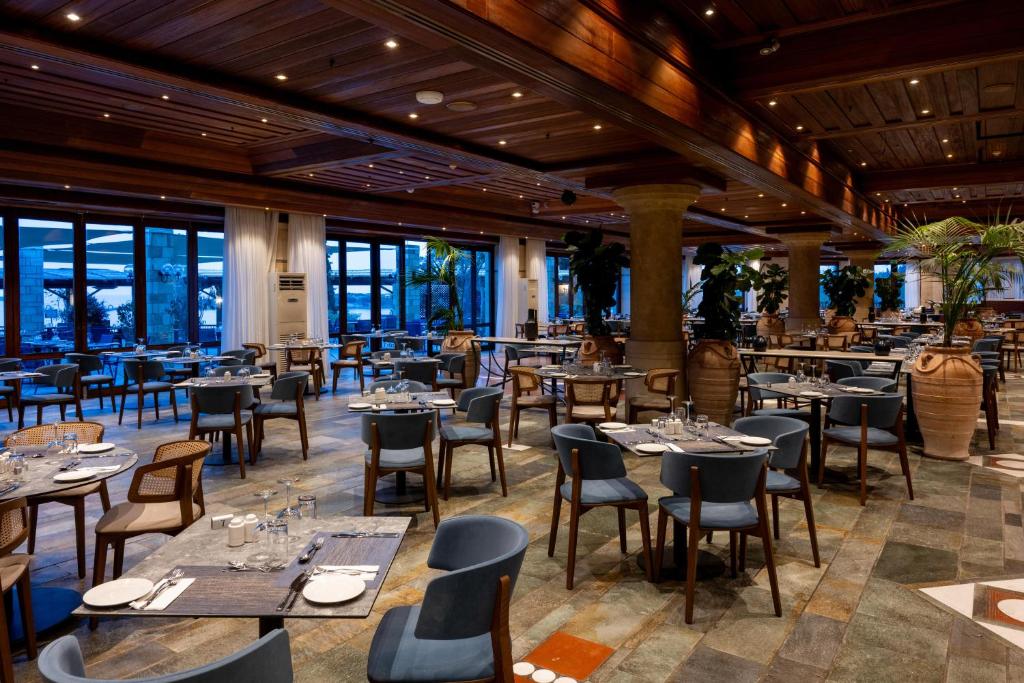 a restaurant with tables and chairs and windows at Coral Beach Hotel & Resort Cyprus in Coral Bay