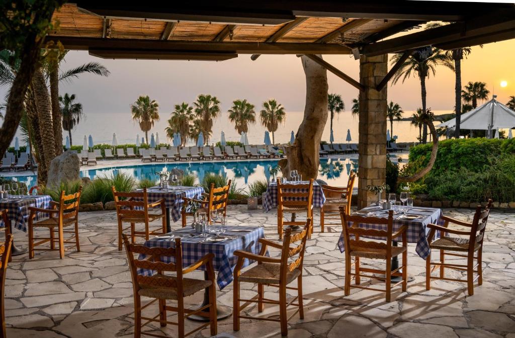 a restaurant with tables and chairs in front of a pool at Coral Beach Hotel & Resort Cyprus in Coral Bay
