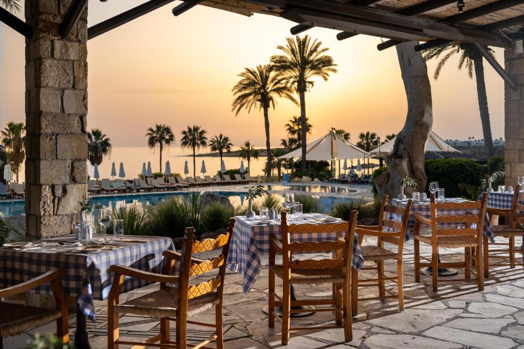 a dining area with tables and chairs next to a pool at Coral Beach Hotel & Resort Cyprus in Coral Bay