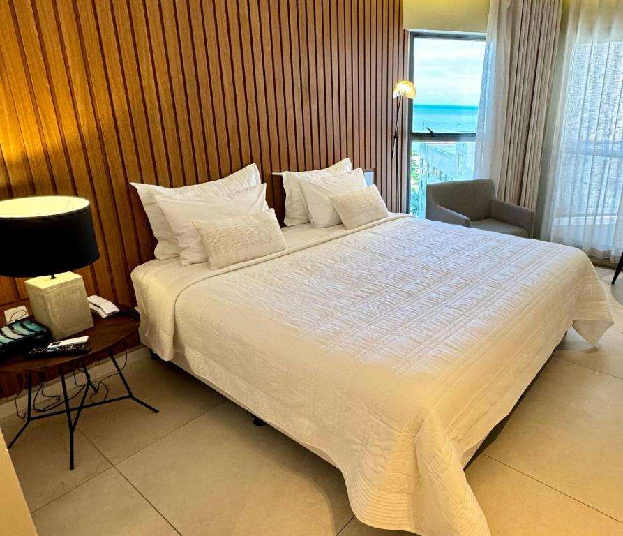 sypialnia z dużym białym łóżkiem, biurkiem i oknem w obiekcie Urban Home Stay - Beira Mar Internacional w mieście Recife