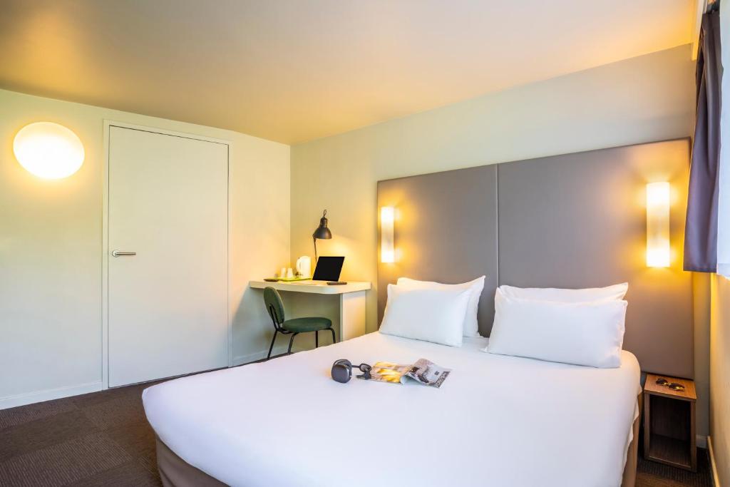 a hotel room with a large white bed and a desk at Campanile Vichy - Bellerive in Bellerive-sur-Allier