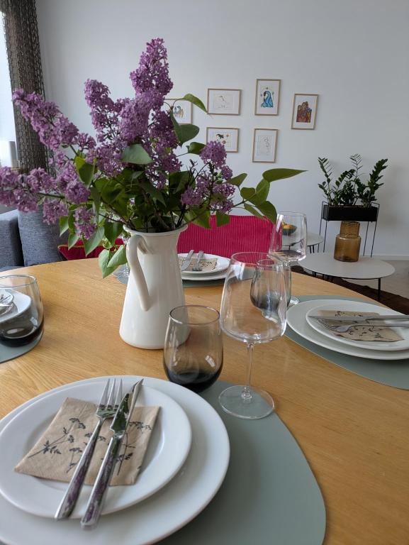 a table with plates and glasses and a vase with purple flowers at Aia kodu in Haapsalu