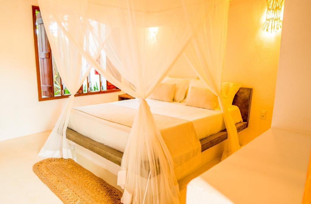a bedroom with a bed with a mosquito net at Vila Vento in Atins