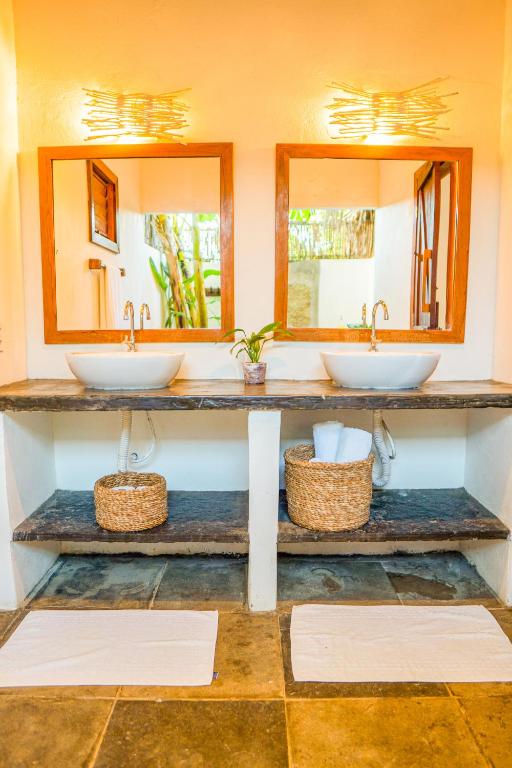 two sinks in a bathroom with two mirrors at Vila Vento in Atins