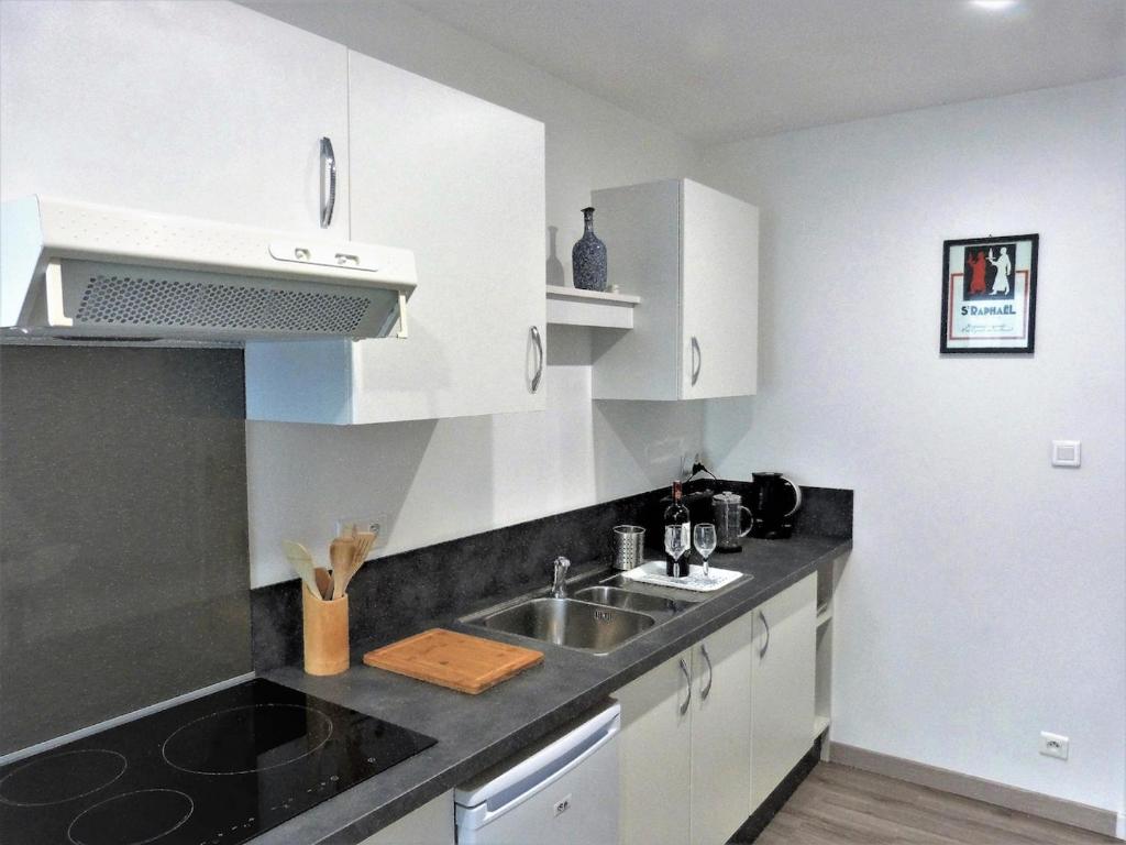 une cuisine avec des armoires blanches et un évier dans l'établissement Le Quarante, à Périgueux