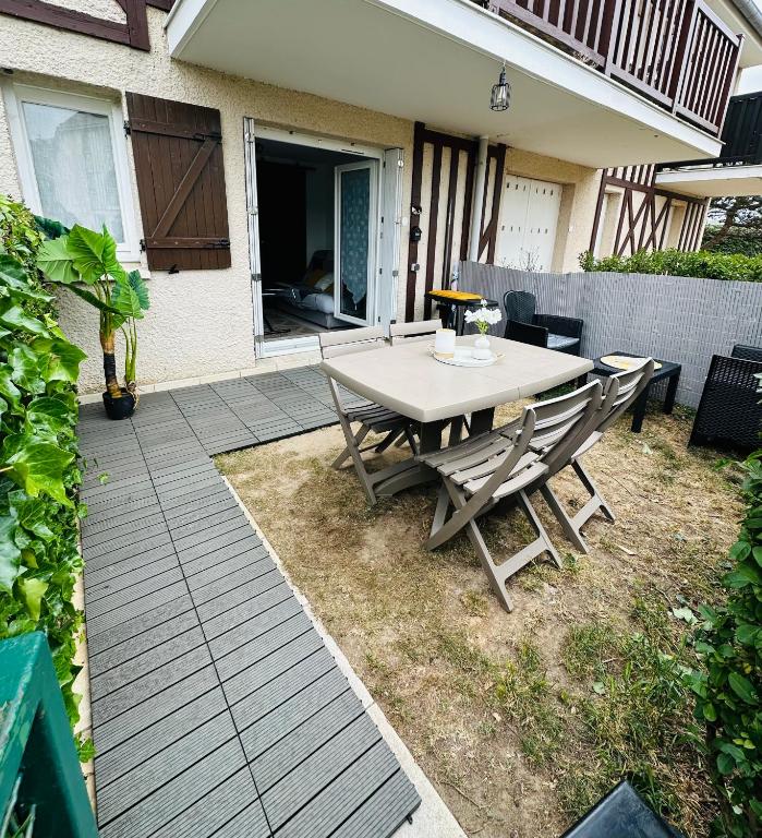 un patio avec une table et des chaises dans une cour dans l'établissement Aux accents maritime et jardin 200m de la mer, à Merville-Franceville-Plage