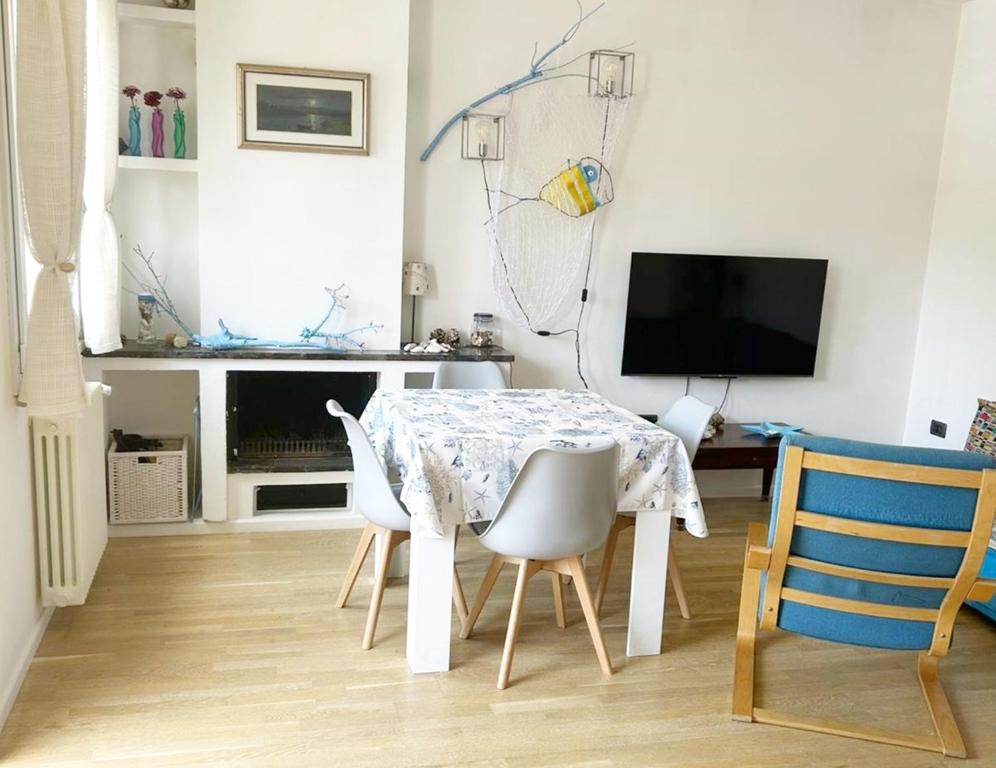 a white dining room with a table and chairs at Casa La Marina a Marina di Cecina by Zoom In Earth in Marina di Cecina