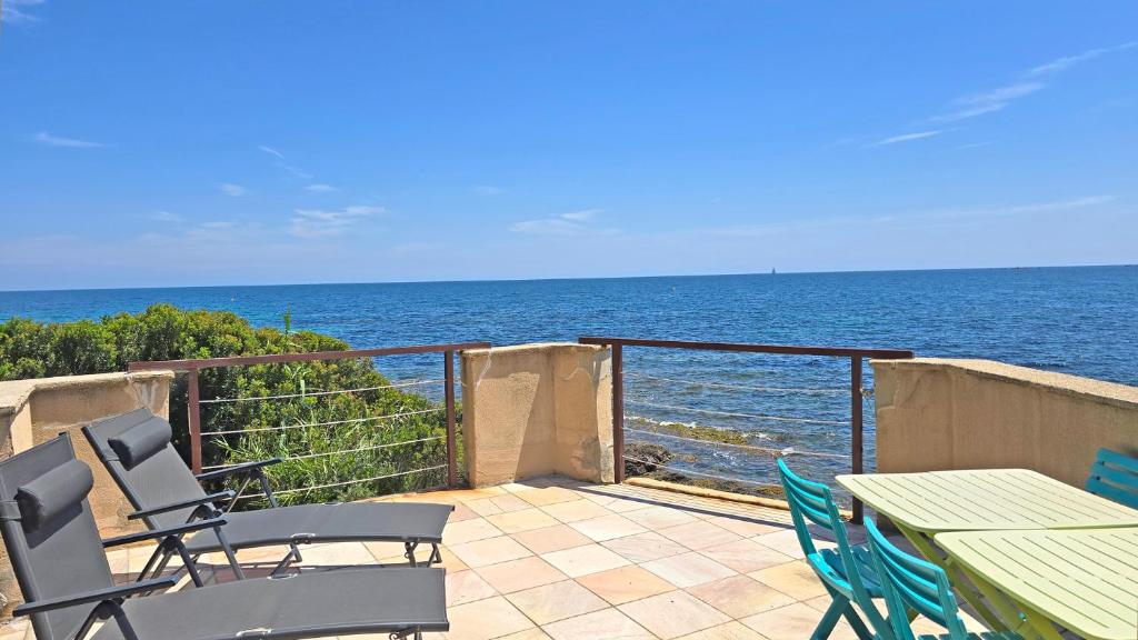 un patio avec une table et des chaises et l'océan dans l'établissement Le Bateau, à Sainte-Maxime