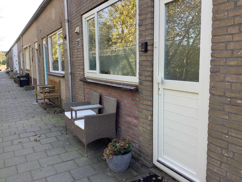 a brick building with two chairs and a door at Zomerhuis Zwart in Egmond aan Zee