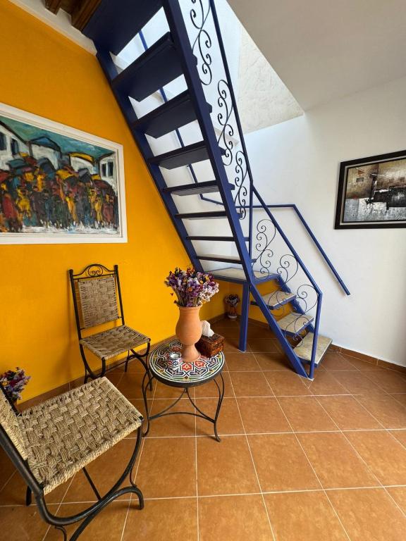 un soggiorno con una scala, un tavolo e delle sedie di Riad Radia a Rabat