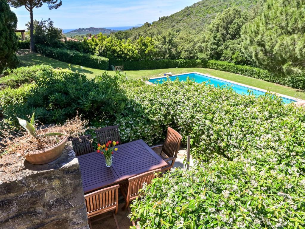 a table and chairs in a garden with a swimming pool at Holiday Home Le Mandrie by Interhome in Punta Ala