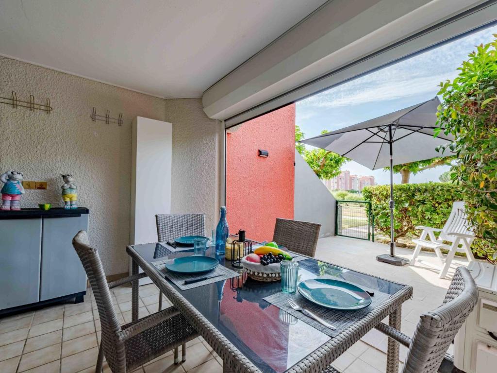 une salle à manger avec une table, des chaises et un parasol dans l'établissement Apartment Caraibes-4 by Interhome, au Barcarès