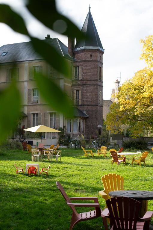 un groupe de chaises et de tables devant un bâtiment dans l'établissement Le Picardeau Gîtes - Nature et Detente, à Nemours