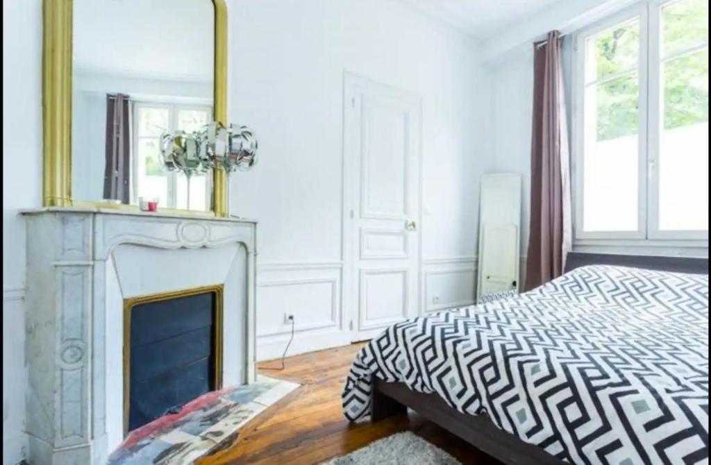 - une chambre avec une cheminée, un lit et un miroir dans l'établissement 3 pièces Arc de Triomphe RDC, à Paris