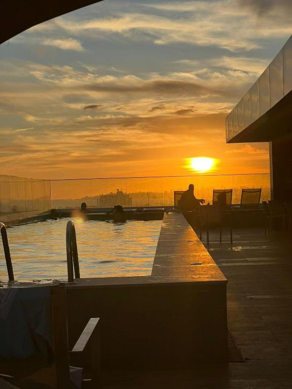 a person sitting on a dock with the sunset in the background at Stella Maris Premium in Salvador
