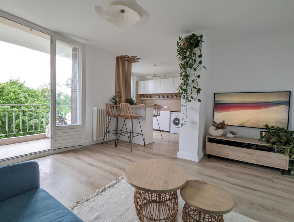 un salon avec une table et une cuisine dans l'établissement T2 au calme, balcon, proche métro, parking gratuit, à Caluire-et-Cuire