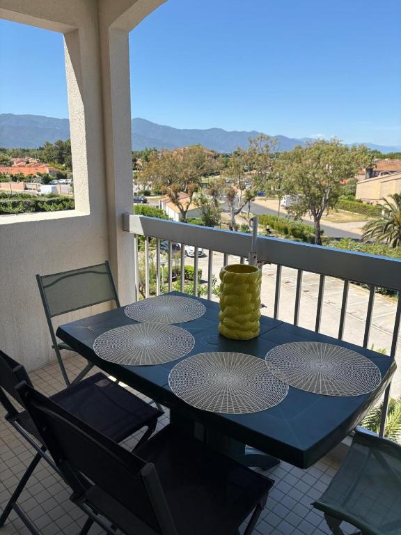 une table bleue avec des chaises et une bougie sur un balcon dans l'établissement Cocon en bord de mer avec piscine, à Saint Cyprien Plage