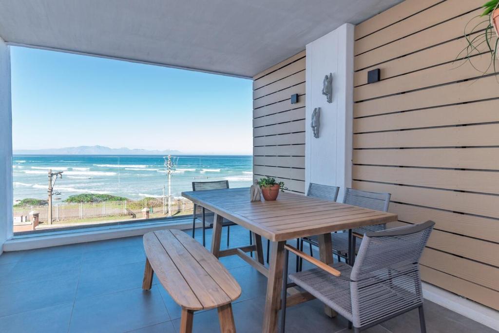 ミューゼンバーグにあるModern 2BR Wavescapes Near Muizenberg Beachの海が見えるバルコニーにテーブルと椅子がある