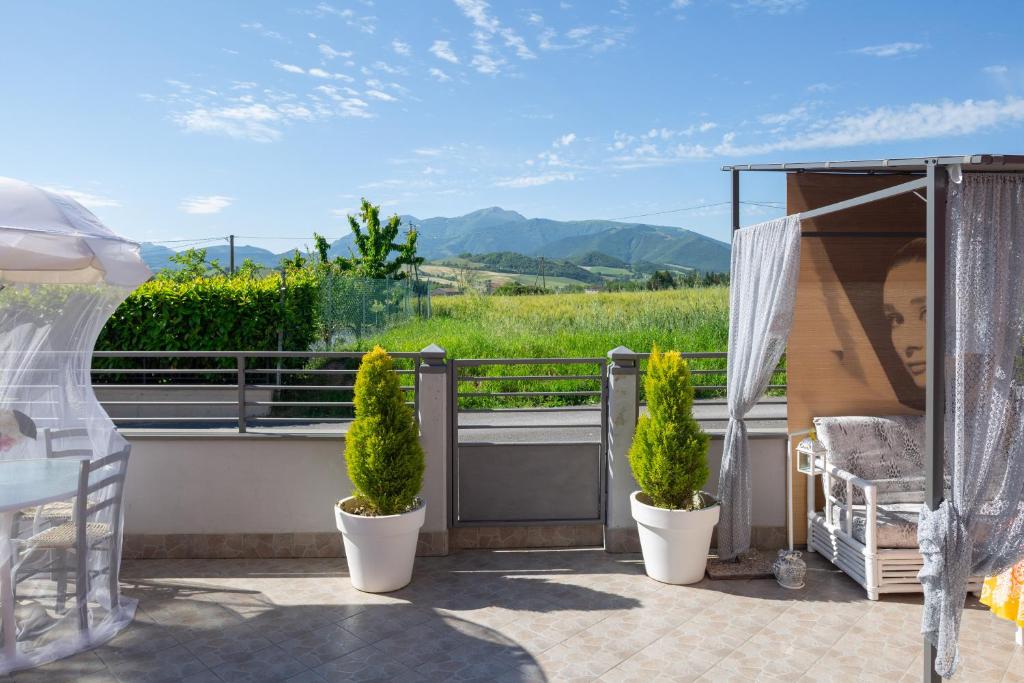 a balcony with two potted plants and a view of a field at Bed & Breakfast Cozy Hills in Cagli