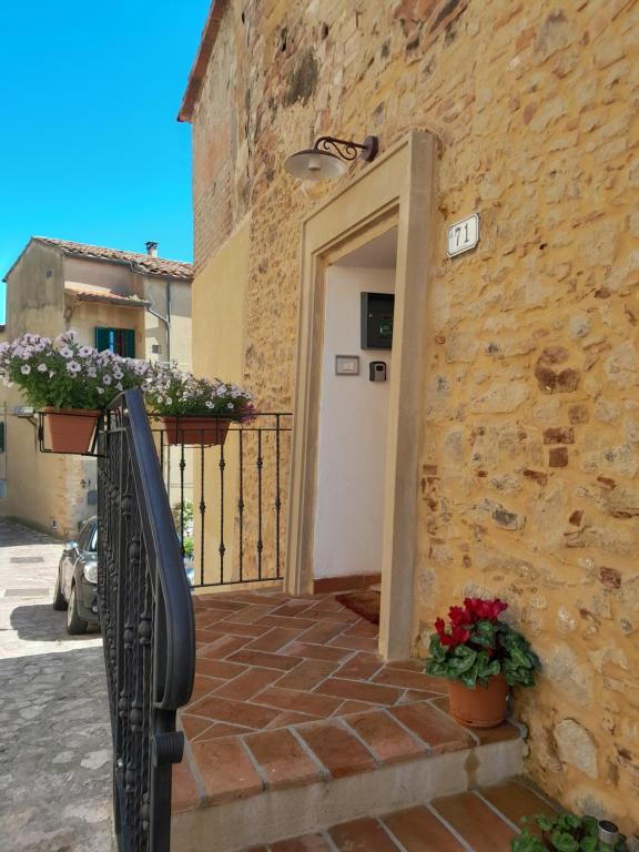 a stone building with a white door and some flowers at Casa Diana Holiday Home in Montescudaio