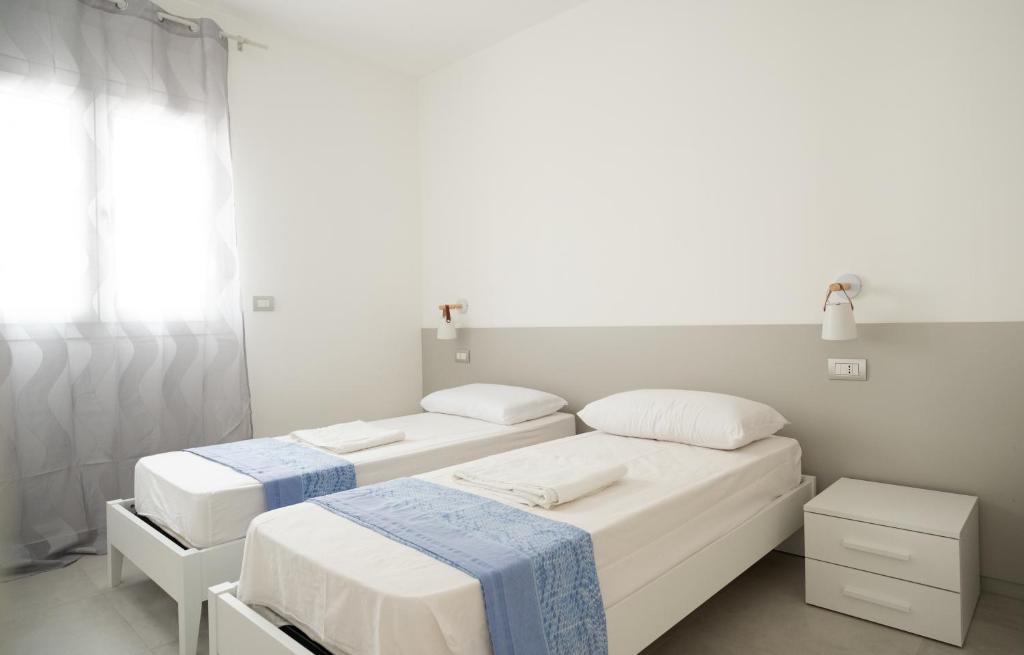 a white room with two beds and a window at Appart NUOVO Sorgenti Sup by Salento Prime in Marina di Pescoluse