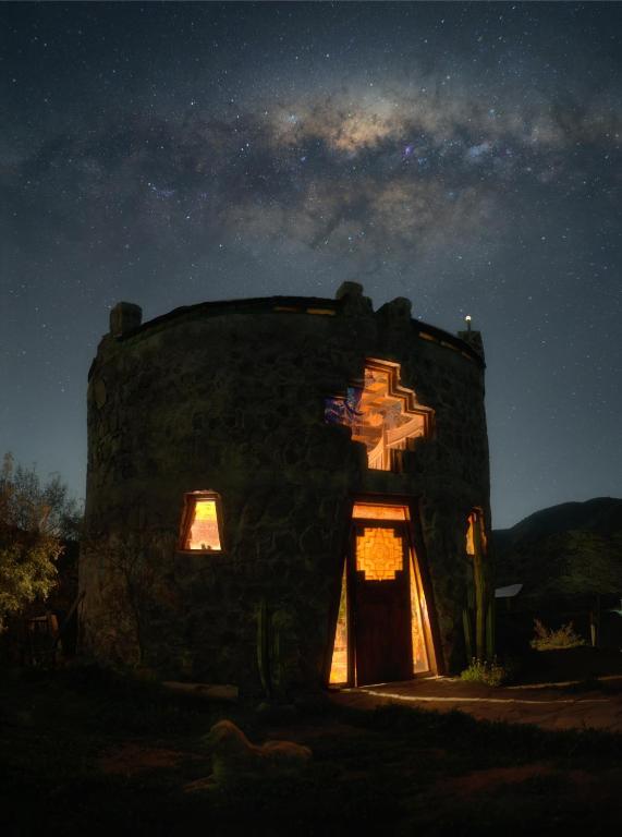 a small stone building with a door at night at Alojamiento y Refugio Cósmico Torreon in Comunidad Campo de Ahumada