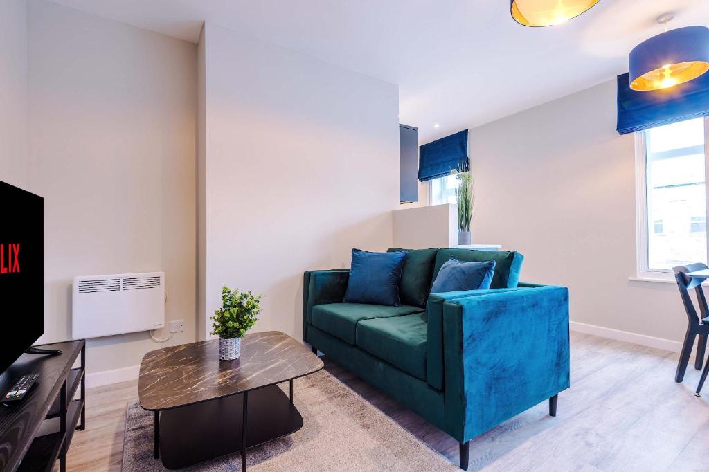 a living room with a blue couch and a table at Elysée Suites - Modern 1 Bed Flat in Southport in Southport