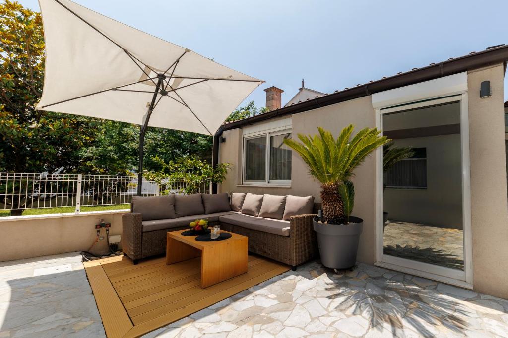 a patio with a couch and an umbrella at Apartment Puntamica in Zadar