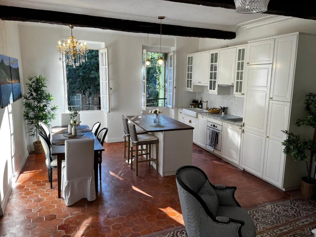une cuisine avec des armoires blanches et une table et des chaises dans l'établissement La MaisonLight Airy Home in the Heart of Pzenas Fontaine, à Pézenas