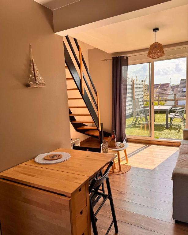un salon avec une table et un escalier dans l'établissement Le Sunset, à Sangatte