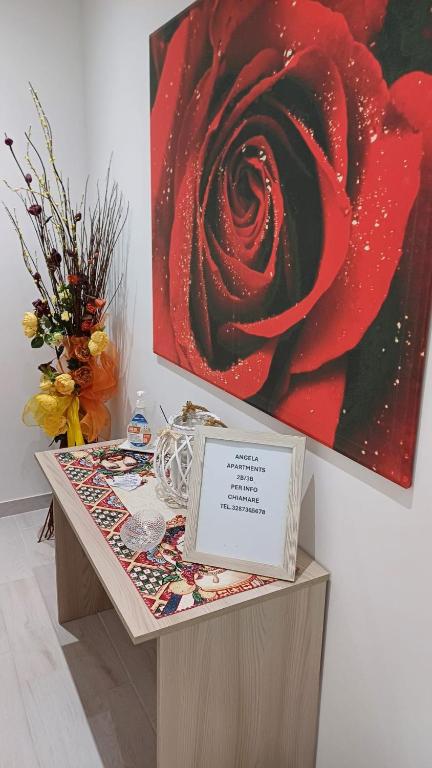 a table with a picture of a red rose on it at Angela apartments in Partinico