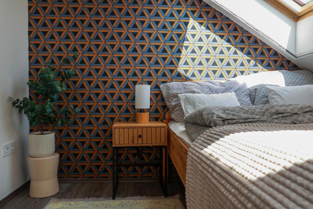 a bedroom with a geometric accent wall and a bed at Heroes Apartment Esztergom in Esztergom