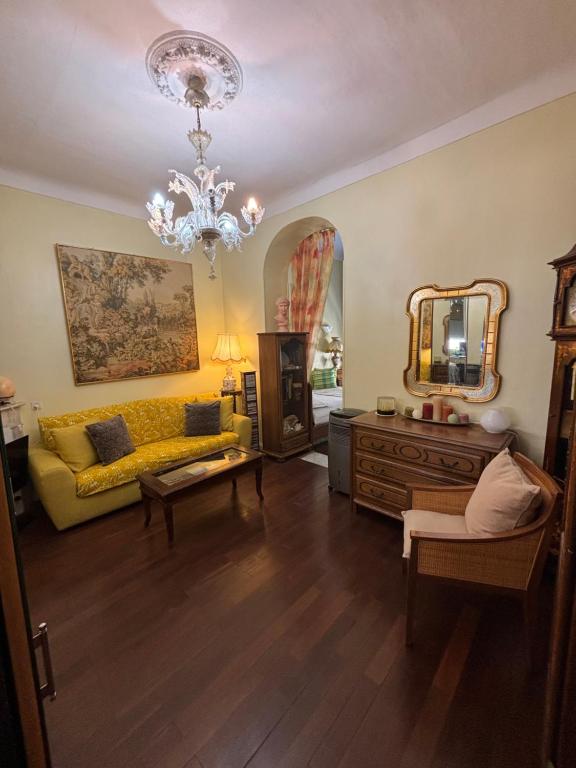 un salon avec un canapé jaune et un lustre dans l'établissement Appartement balcon de Monaco, à Beausoleil