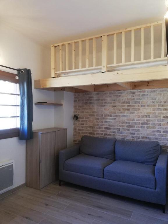 - un canapé bleu dans une chambre avec un mur en briques dans l'établissement Studio refait à neuf au cœur du village, à Péone