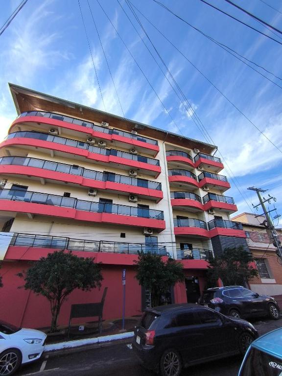 a tall building with cars parked in front of it at Dpto a pasos de la playa San José in Encarnación