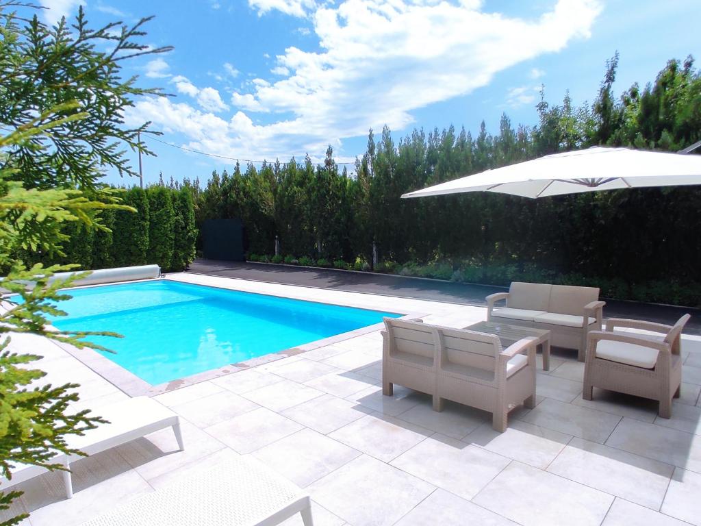 a swimming pool with chairs and an umbrella next to it at Natural Cottage Una in Bihać