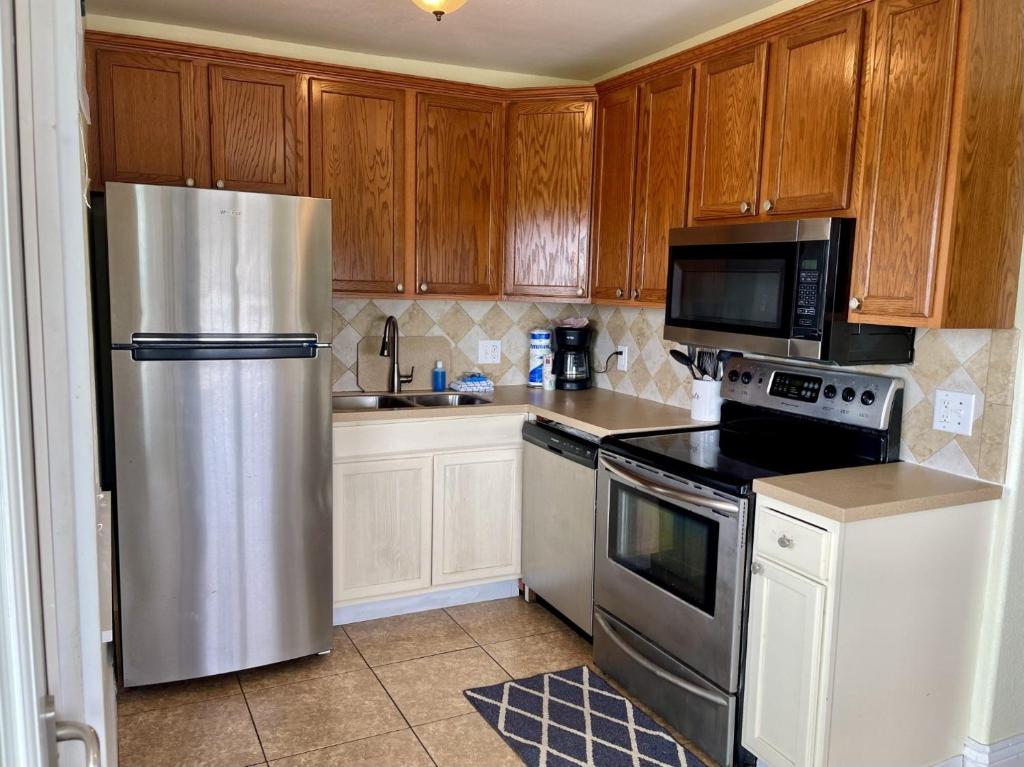 a kitchen with wooden cabinets and a stainless steel refrigerator at Beachgate Condo Suites and Hotel 121 condo in Port Aransas