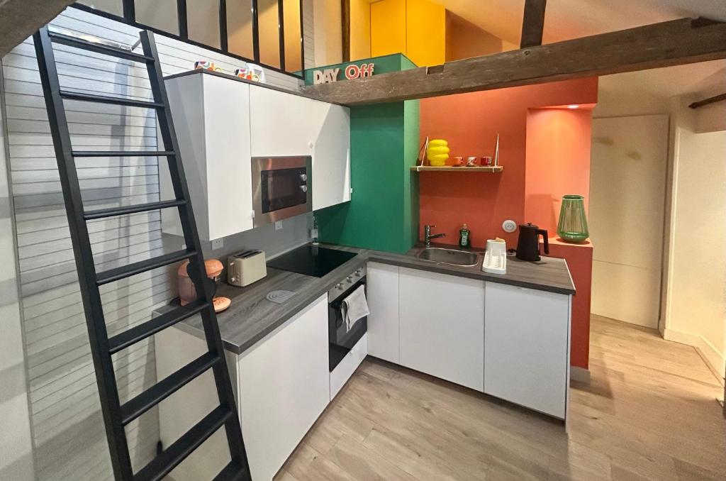 une cuisine en mezzanine avec des placards blancs et une échelle dans l'établissement Le Refuge Saint Sauveur, à Caen