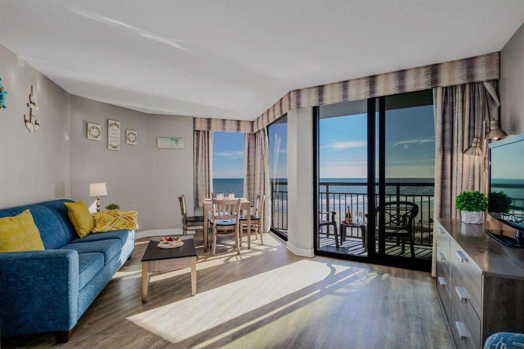 een woonkamer met een blauwe bank en een balkon bij Winter Rates! Calming Oceanfront Suite, Dogs OK! 410 in Myrtle Beach