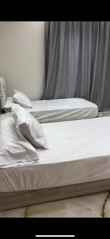 two beds with white sheets and pillows in a room at شقه مفروشه in Cairo