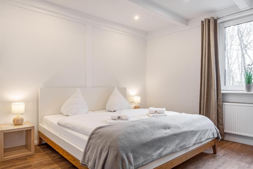 a white bedroom with a large bed and a window at Ferienwohnung Pellwormer Küstenkind in Pellworm