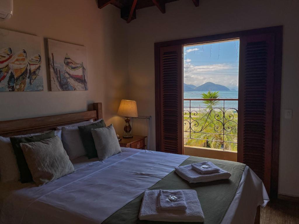 a bedroom with a bed with a view of the ocean at Casa Melville Hospedagem - Sua Casa de Alto Padrão no Coração de Ubatuba! in Ubatuba