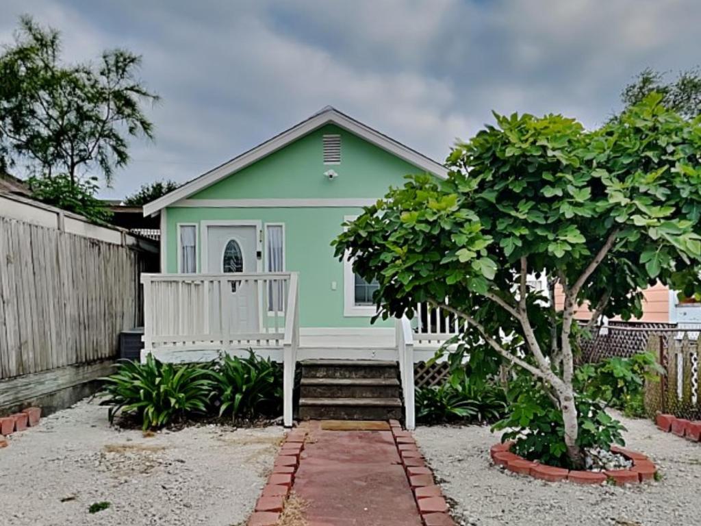 una pequeña casa verde con porche blanco en Sugar Shack Bungalow, en Galveston