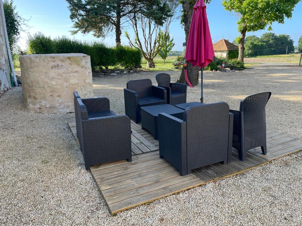 eine Gruppe von Stühlen und ein Sonnenschirm auf einer Terrasse in der Unterkunft Le Plessis in Parçay-les-Pins