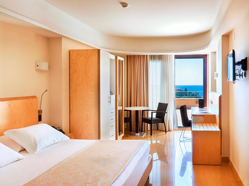 a hotel room with a bed and a table with a view at Taormina Panoramic Hotel in Taormina