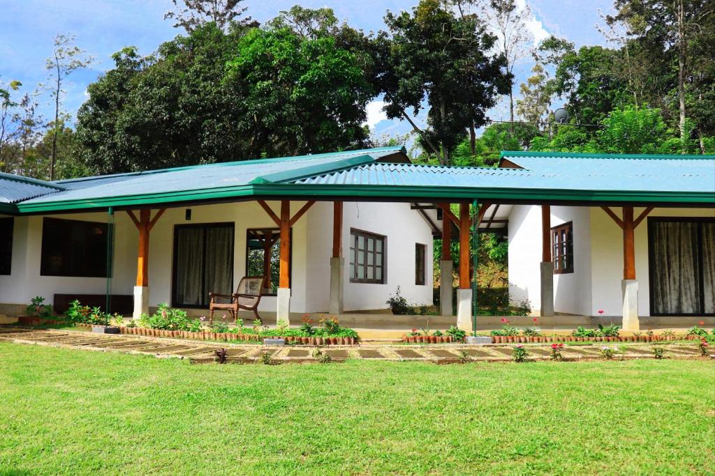 a small white house with a blue roof at The 6th Milepost Tea Bungalow Bandarawela in Bandarawela